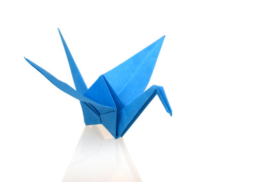 A blue origami bird standing on white