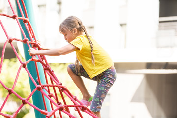 Young girls poking head through climbing rope activity using it as frame.