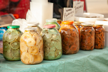 Pickled Different mushrooms in large glass jars at the russian rural fair. Ginger