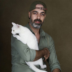 Bearded man hugging his white cat, indoors portrait.