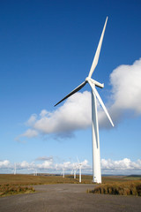 Fototapeta premium Single wind turbine with blue sky in a vertical format - UK. Clean and renewable energy concept. 