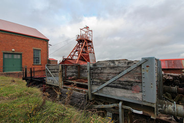 Fototapeta na wymiar Big Pit was a working coal mine from 1880 to 1980. It is now obsolete and closed. Exterior of an old building with broken and discarded machinery scattered on the ground.