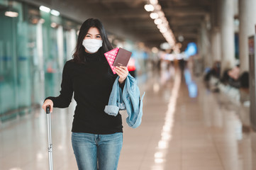 Asian woman tourist wearing face mask holding passport with luggage during coronavirus or covid-19...