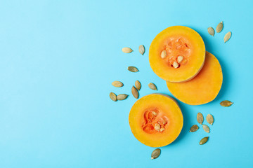 Squash slices and seeds on blue background, space for text