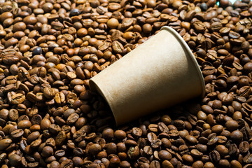 Pile of fresh aromatic coffee beans and paper mockup cup.