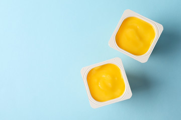 Plastic cups of yellow yogurt on blue background