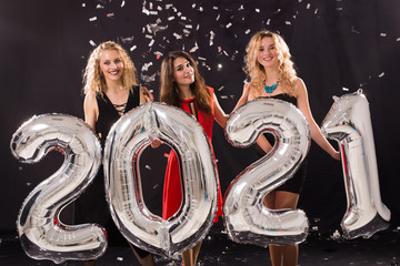 Party, people and new year holidays concept - cheerful young women celebrating new years eve 2021