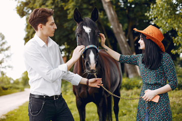 Couple in a summer park. Pair standing with a horse. Girl in a green dress