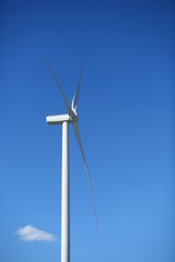 Profile view of wind power energy generator against blue sky