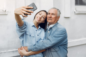 Grandfather with granddaughter. Girl teaching her grandfather. Using a phone.