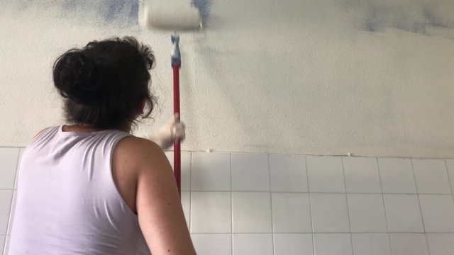 Mujer pintando la pared de su casa