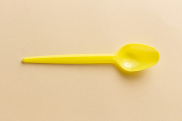 Yellow plastic spoon on a yellow background.
