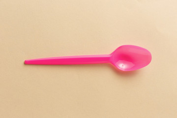Pink plastic spoon on a yellow background.