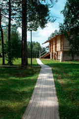 a wooden path leads from the forest to a wooden house