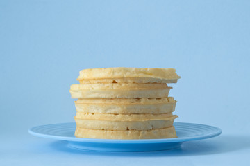 Round breakfast waffles stacked on blue plate