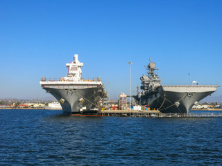 Two aircraft carriers parked next to each other and being repaired and readied in San Diego bay where the US navy naval base is located.