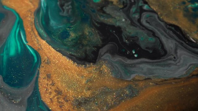 Grren, white and shiny gold colors oil paint pouring close up. Fluid Art painting. Moving flowing stream of liquid paint. Decorative abstract background