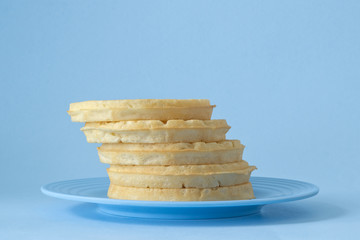 Round breakfast waffles stacked on blue plate