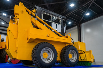 Cleaning equipment for the streets. Machine with brushes for sweeping dust. Street cleaning in the city. Yellow sweeper in the exhibition hall. Communal service.