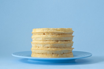 Round breakfast waffles stacked on blue plate