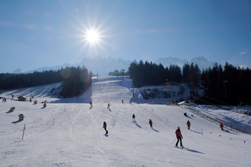 Silhouettes of skiers sliding down the slope on a beautiful sunny day in dolomites. San Candido (Innichen), South Tyrol, Italy