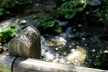 Dettaglio di staccionata di legno lungo un ponte che attraversa un ruscello, fiume