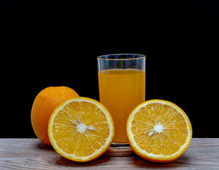 Orange juice in a glass and an orange fruit on the ground
