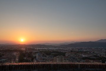Obraz premium Aerial panoramic sunset view of residential district with buildings of Brescia city and Alps mountain range, blue cloudy sky background, Lombardy, Italy. Brescia Castle.