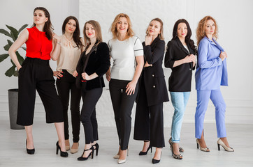 A group of women dressed in business style are standing together and posing at the camera.