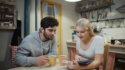 Young couple drinking tea and discuss a book on a kitchen