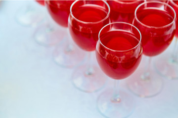 A row of glasses with red drinks, juice, champagne or wine at a party. Catering. Glassware on the table with a white tablecloth. Festive buffet for the holiday.
