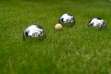 Boccia balls made of chromed steel lie on a grass surface. Play for your own garden.