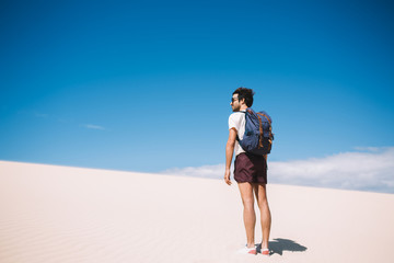 Male traveller standing under heating sun rays during journey to White sands national park, guy wanderlust standing outdoors with breathtaking view of desert and sky horizon over dry uninhabited lands