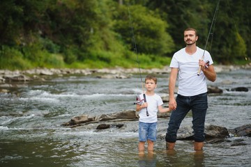 Fototapeta premium Father teaching son how to fly-fish in river