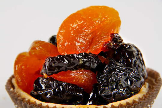 Round pie crust, with prunes and candied apricots inside. Sweet delicious. White background.