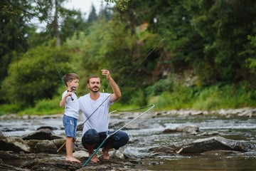 Father and son fishing. Father with his son on the river enjoying fishing holding fishing rods