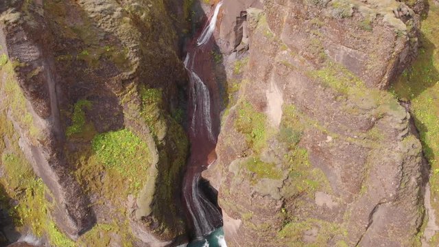 Aerial images with beautiful colors and textures in the Fjaðrárgljúfur canyon in southern Iceland. A waterfall rushes into the canyon.