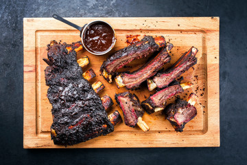 Traditional Barbecue burnt beef ribs St Louis style sliced and offered as top view on a rustic...
