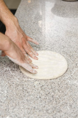 Making dough by male hands on table background.