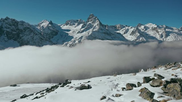 Snow capped mountains above clouds in a blue sky in sunny weather