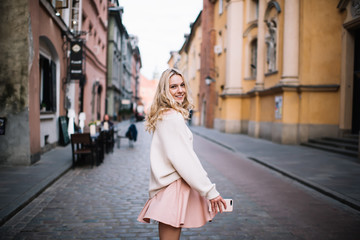 Fototapeta premium Cheerful blonde young woman with smartphone on street