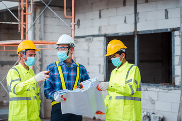 Engineers and construction workers put on a mask to protect against the Corona virus or Covid-19 during construction design work.