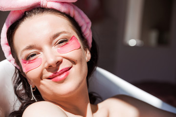 A beautiful young woman in a pink cosmetic bandage and with pink birds under her eyes poses in...