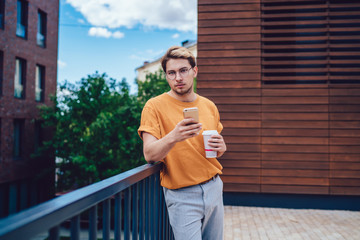 Fototapeta premium Calm male with smartphone and beverage on terrace