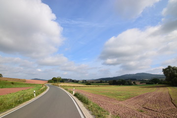 Fototapeta na wymiar Sommerlandschaft in Nordhessen mit leerer Landstraße