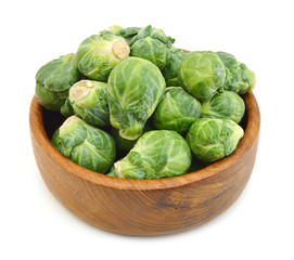 freshly brussel sprouts and some whole ones in wooden bowl on a white background