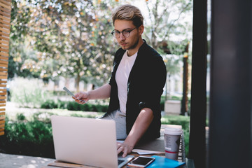 Focused man interacting with laptop while examining reports working in garden