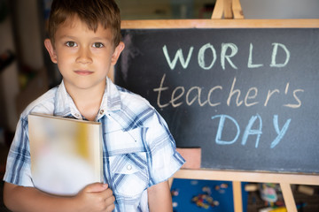 World Teacher's Day greeting, pupil boy near the chalkboard, chalk inscription text