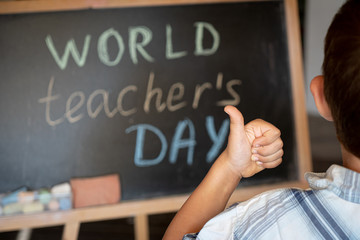 World Teacher's Day greeting, pupil boy near the chalkboard, chalk inscription text