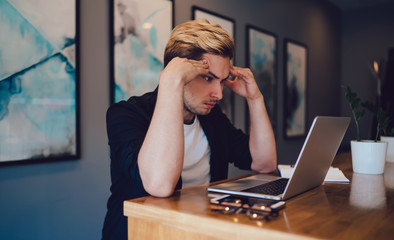 Tired guy thinking over project in workplace